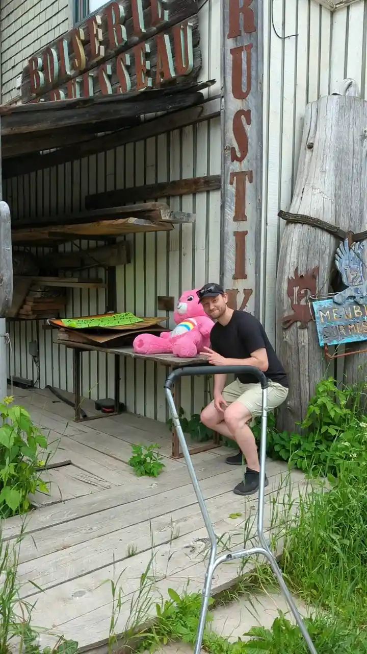 Un homme pose devant une boutique avec une peluche rose.